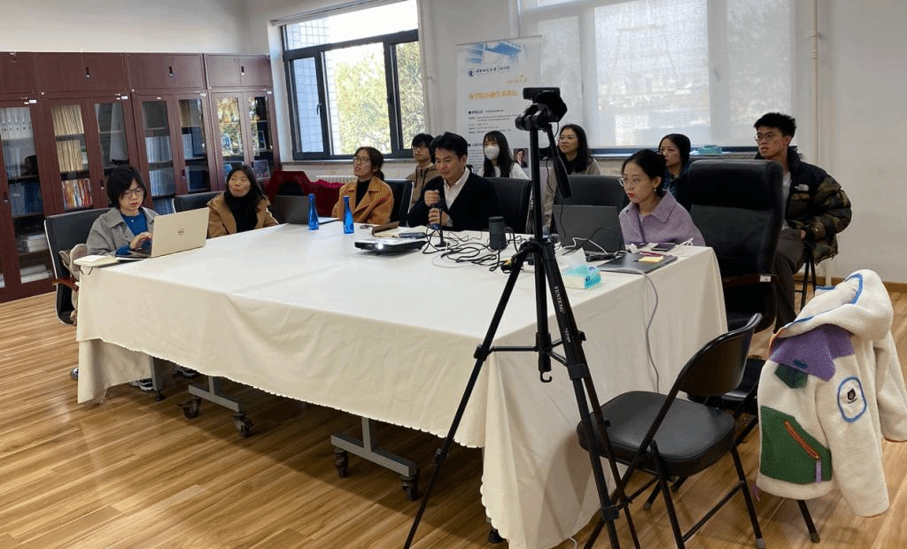 A group of people sitting around a table with a camera on itDescription automatically generated with medium confidence